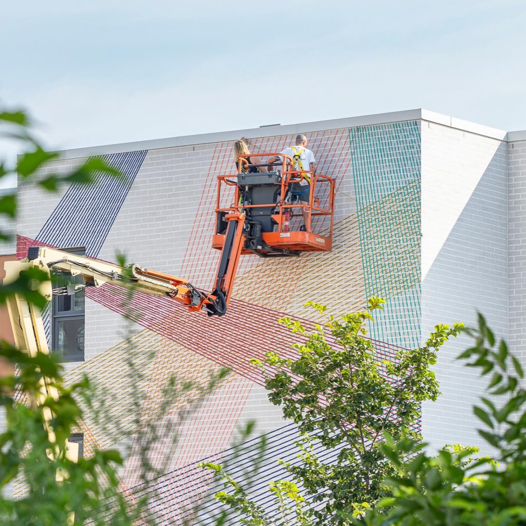 Cyndie Belhumeur painting Intertwined Perspectives mural on residential building