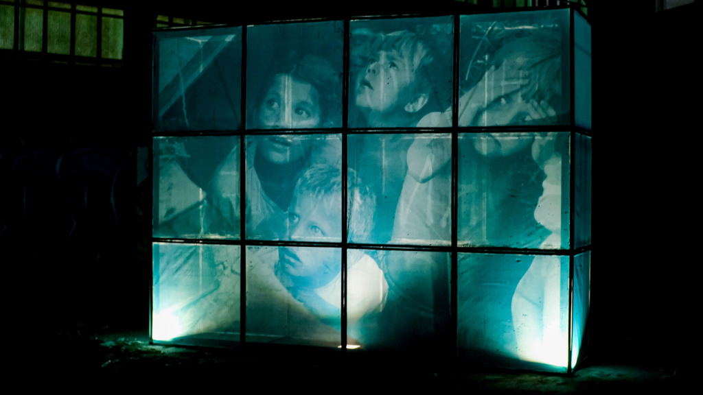 Archival photograph of Soviet children illuminated across painting screens in Ricardo Romero’s THE WORLD BURNS WHILE WE SCROLL.