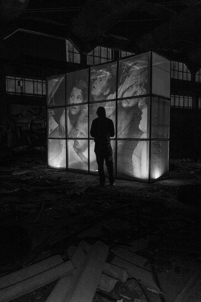 A silhouetted Romero stands before Ricardo Romero’s illuminated wartime image of Soviet children.