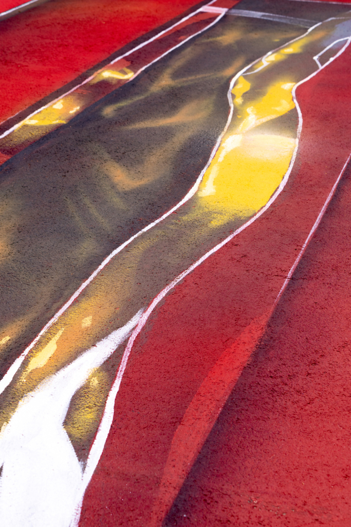 Close-up of the yellow, black and white reflective effects painted by Spok Brillor across the red surface of Hard Court 2.