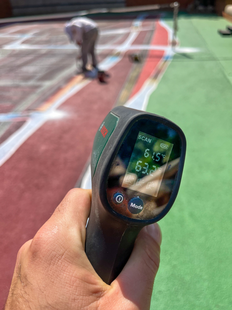 Infrared thermometer recording temperatures above 60°C while Spok Brillor works on Hard Court 2 at Casa Axis.
