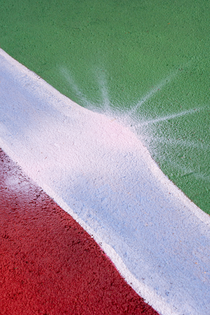 lose-up of Spok Brillor’s sprayed white linework revealing the textured tennis-court surface beneath Hard Court 2.